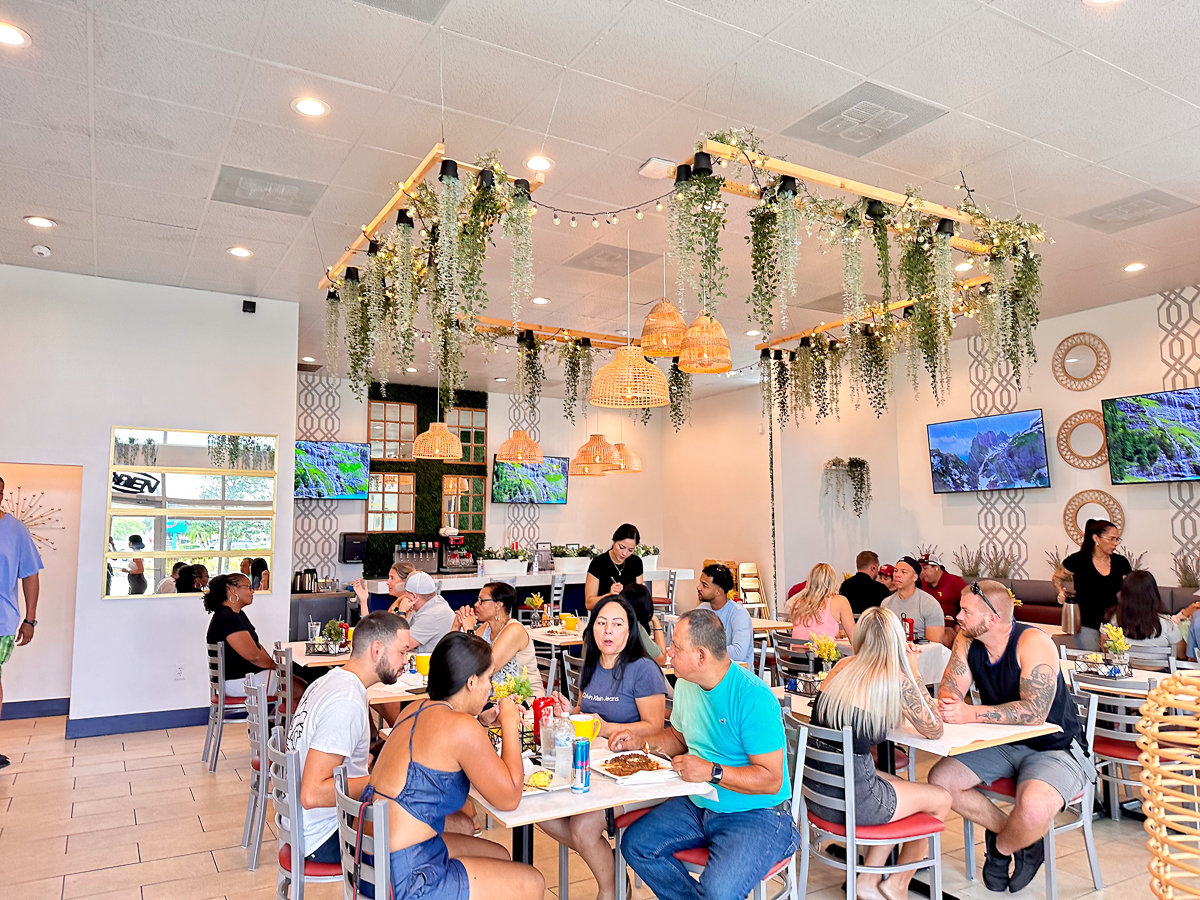 people sitting at tables with greenery and brown decor hanging from the ceiling